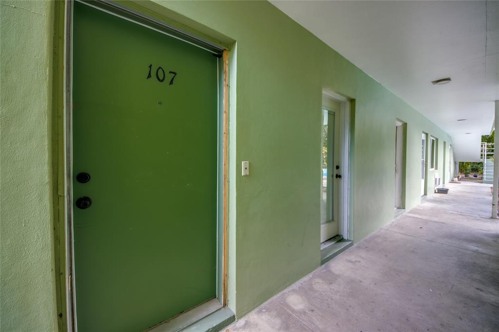 A green exterior door labeled 107 opens onto a covered concrete walkway — 2544 1ST STREET UNIT 107, FORT MYERS, FL