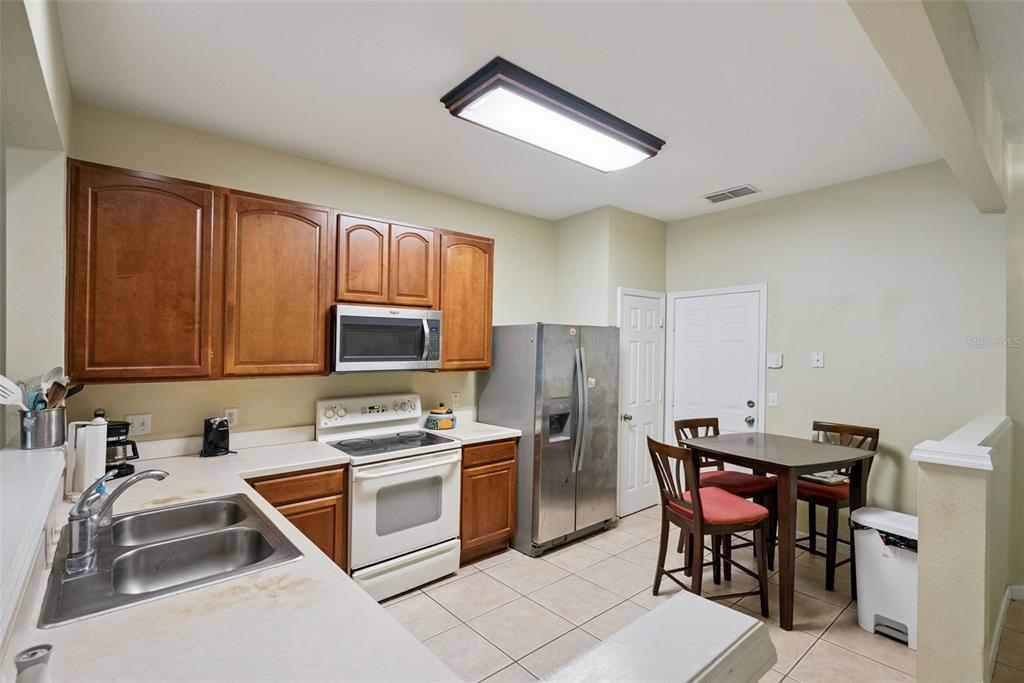 A kitchen with wood cabinets, stainless steel appliances, a dining table, and tile flooring — 1540 FLORENTINO LANE, WINTER PARK, FL