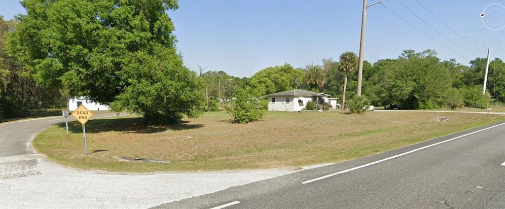 A grassy corner lot with a small house, a large tree, and a dead end sign — 2499 N WOODLAND BOULEVARD, DELAND, FL
