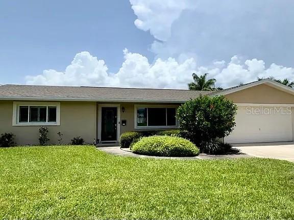 A single-story house with a tan exterior, a front lawn, and an attached two-car garage — 4052 14TH WAY NE, ST PETERSBURG, FL