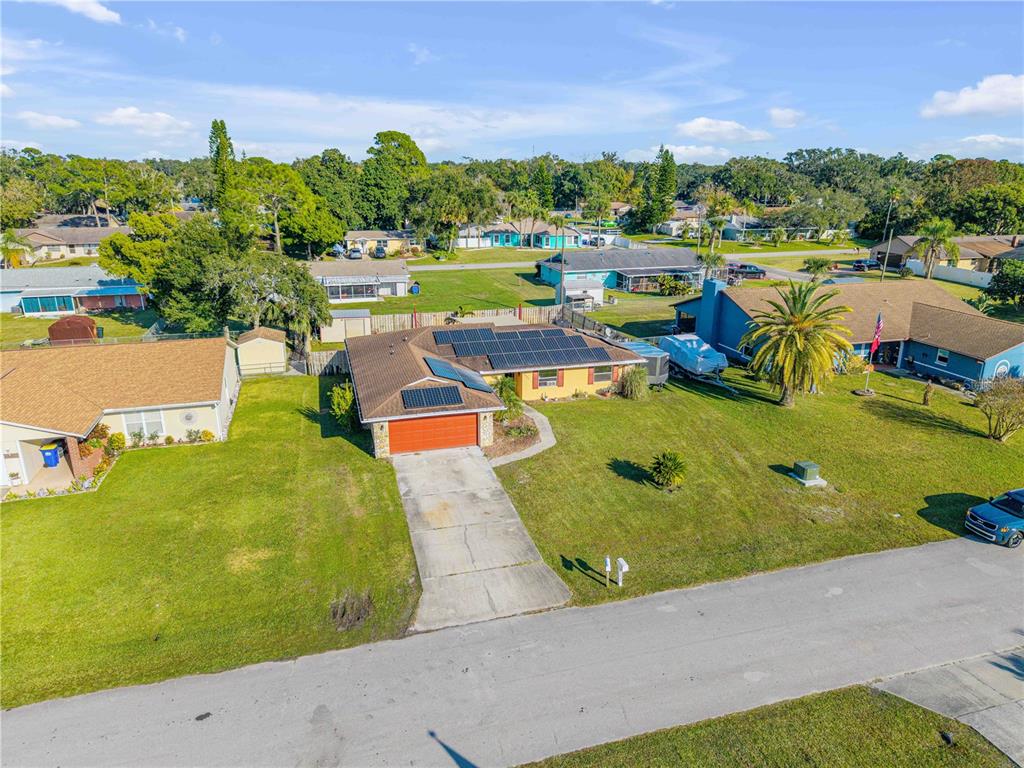 An aerial view shows a single-story house with solar panels on the roof and a driveway — 2425 TRAVELERS PALM DRIVE, EDGEWATER, FL