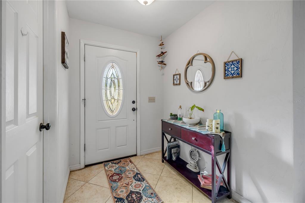 An entryway features a white front door, tile flooring, and a dark wood console table — 2425 TRAVELERS PALM DRIVE, EDGEWATER, FL