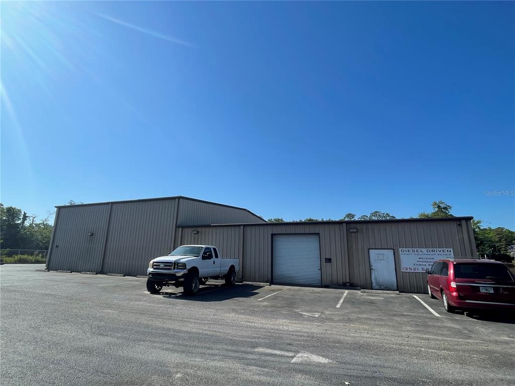 A tan metal industrial building with a roll-up door and two parked vehicles in front — 195 WENDELL AVENUE UNIT A, GROVELAND, FL