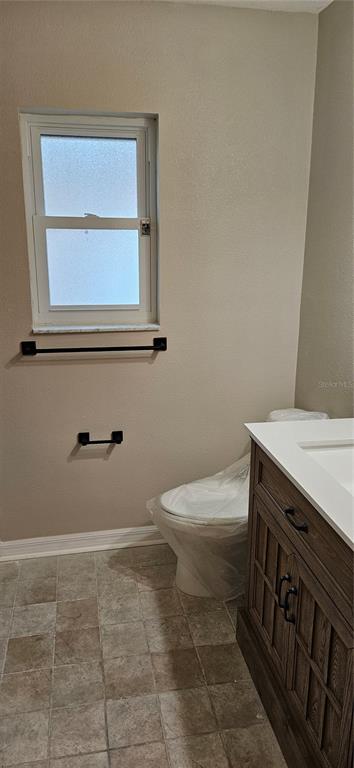 A bathroom features a vanity, a toilet covered in plastic, and a window with hardware — 3186 BENTLEY DRIVE, PALM HARBOR, FL