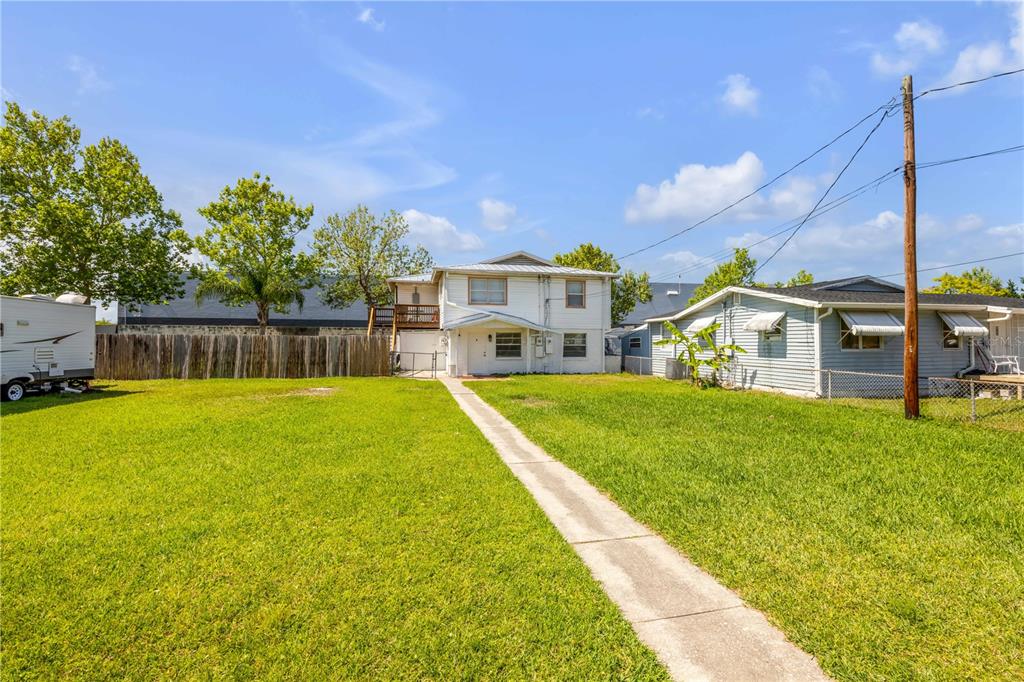A two-story white house stands at the end of a long concrete walkway — 1051 JUNE TERRACE, DAYTONA BEACH, FL