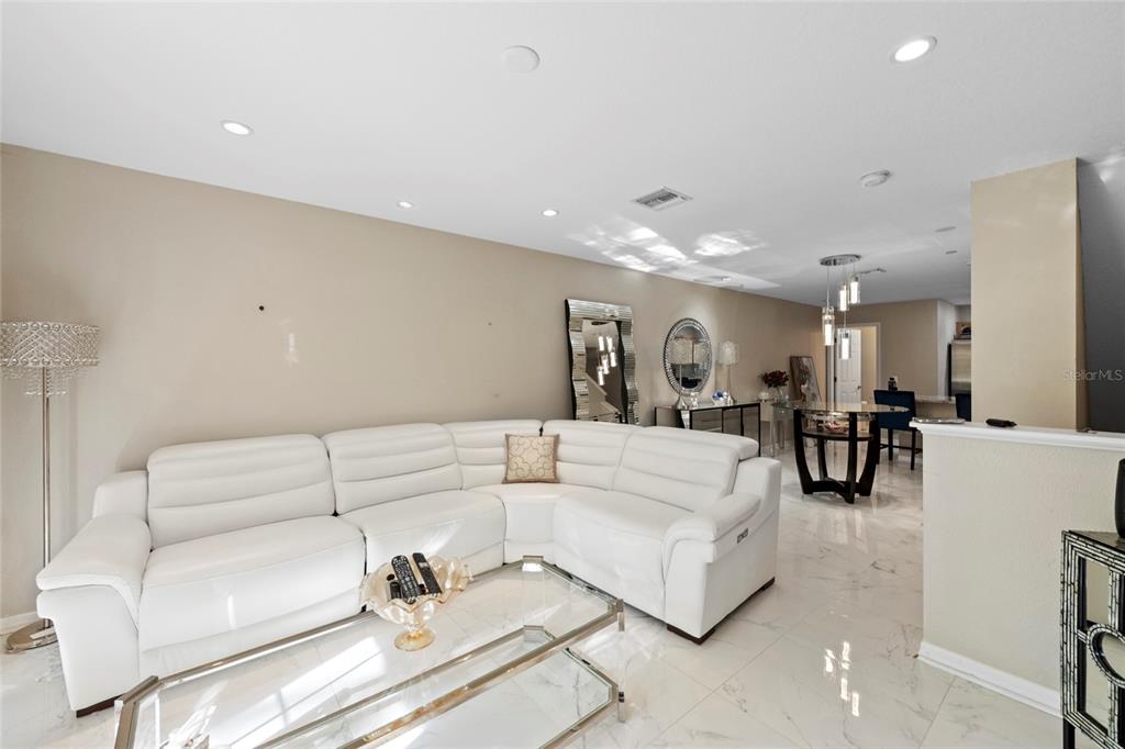 A white sectional sofa sits in a living room with marble floors and recessed lighting — 8825 WHITE SAGE LOOP, LAKEWOOD RANCH, FL