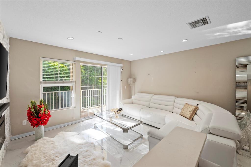 A living room features white tile floors, a white sectional sofa, and a sliding glass door — 8825 WHITE SAGE LOOP, LAKEWOOD RANCH, FL