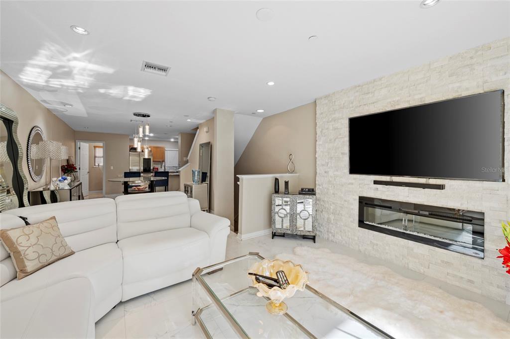 A living room features a white sofa, a glass coffee table, and a stone fireplace — 8825 WHITE SAGE LOOP, LAKEWOOD RANCH, FL