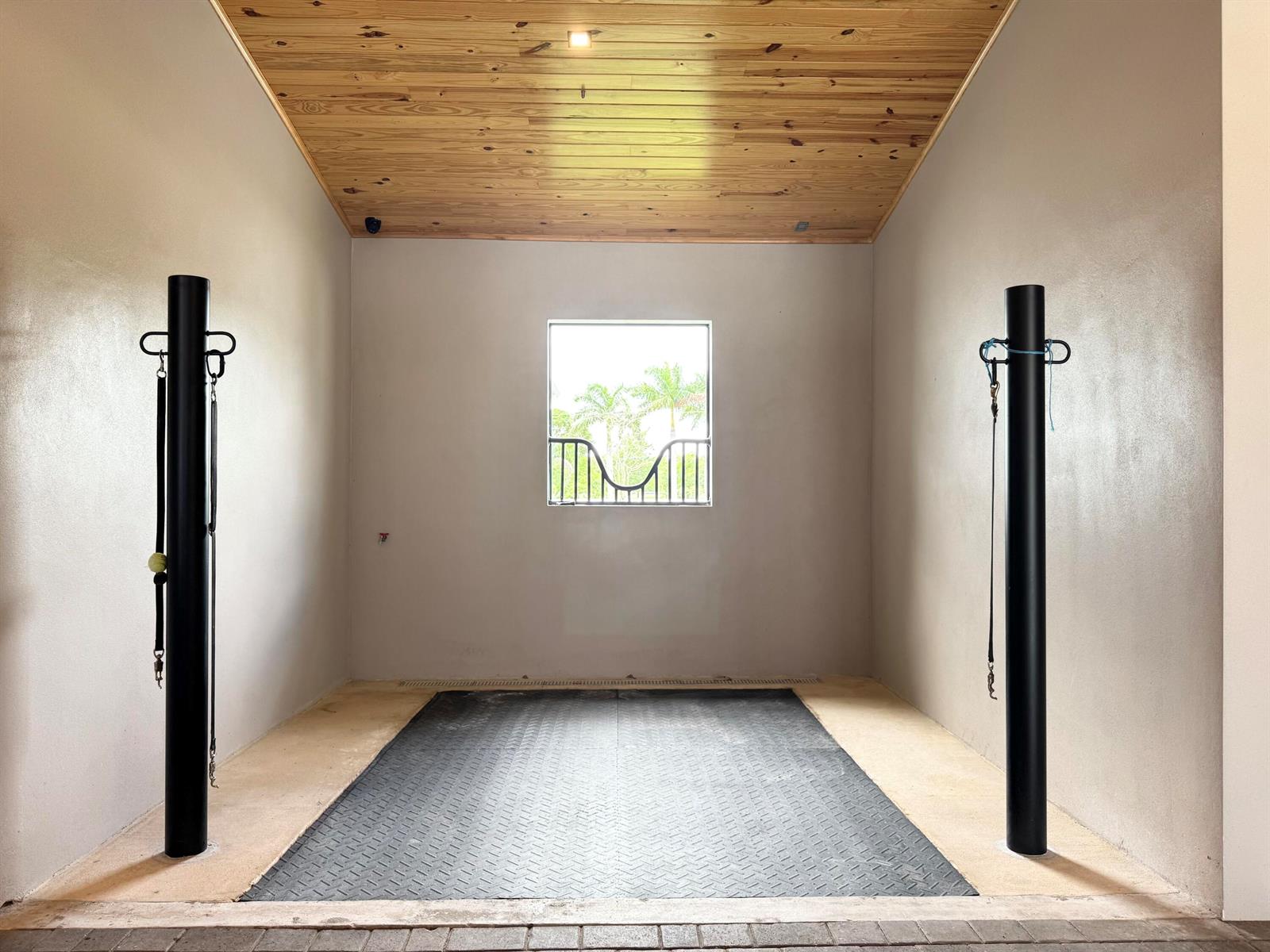 A horse grooming stall with black posts, rubber flooring, and a wood-paneled ceiling — 19550 Egret Lane, Loxahatchee FL 33470, LOXAHATCHEE, FL