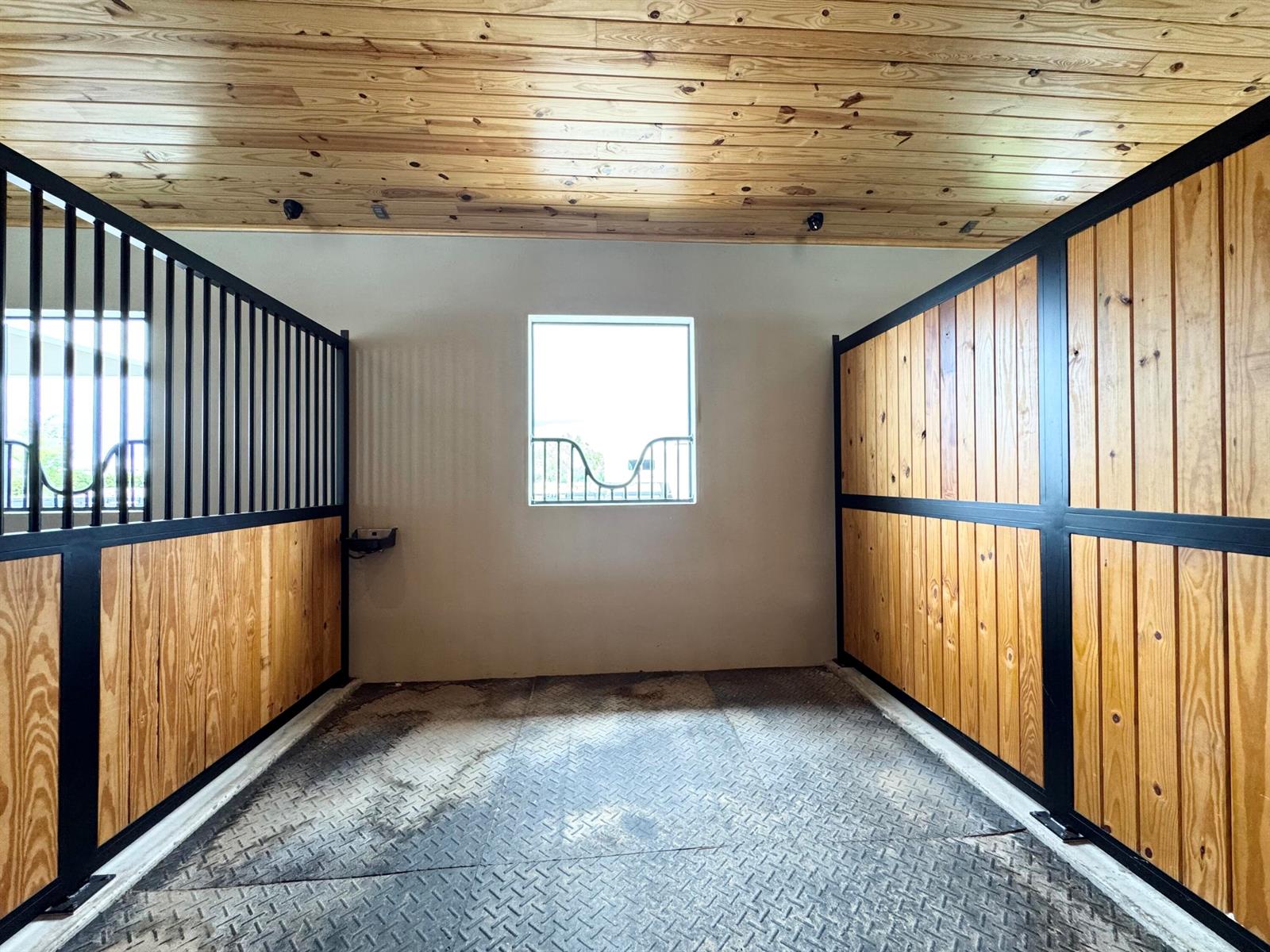 A horse stall with wood-paneled walls, a metal floor, and a central window — 19550 Egret Lane, Loxahatchee FL 33470, LOXAHATCHEE, FL