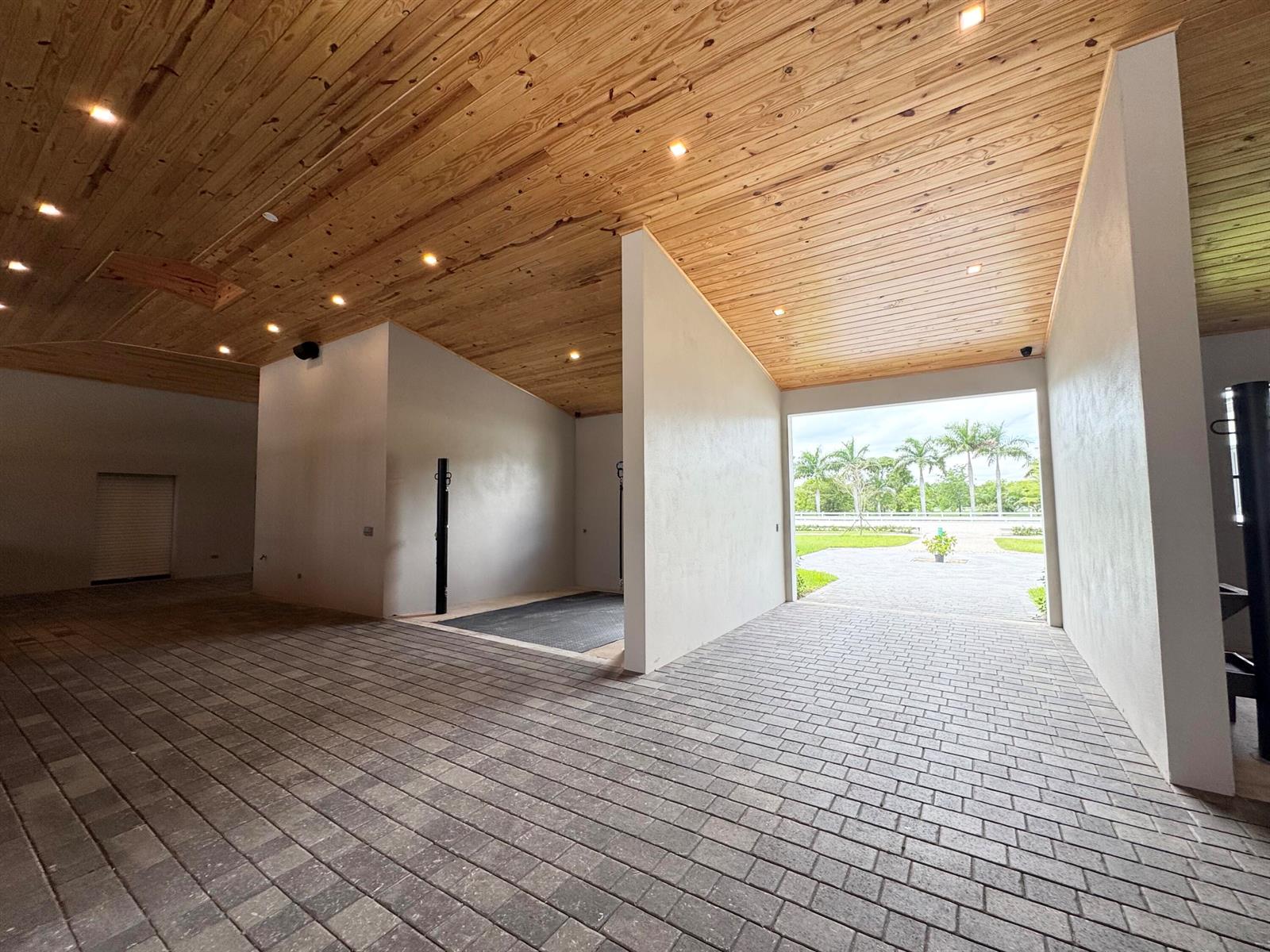 An open-air barn features a wood-paneled ceiling, paved brick flooring, and white walls — 19550 Egret Lane, Loxahatchee FL 33470, LOXAHATCHEE, FL