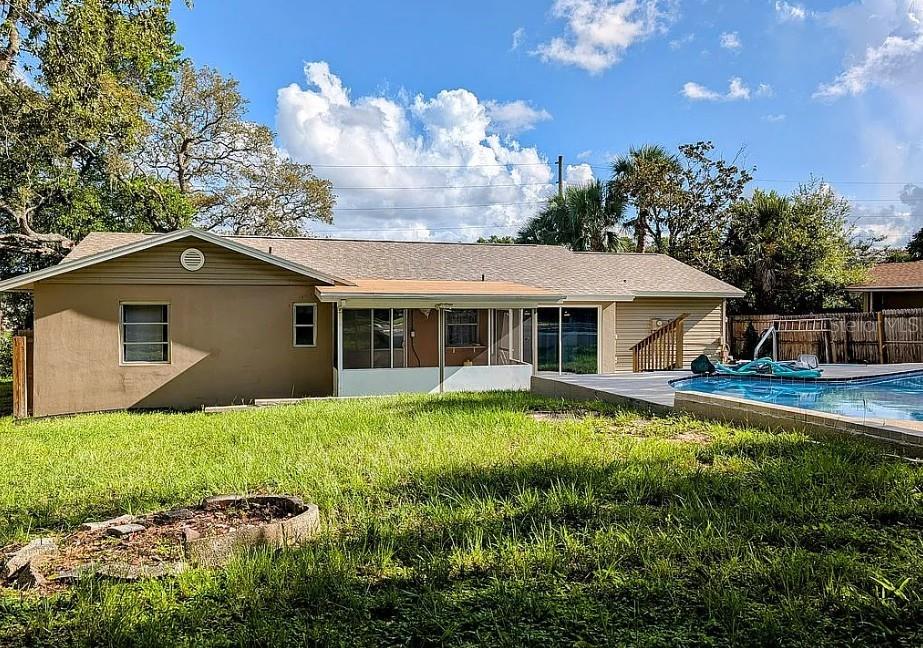 The backyard features a tan house with a screened porch and an in-ground swimming pool — 6070 ASHLAND DRIVE, SPRING HILL, FL