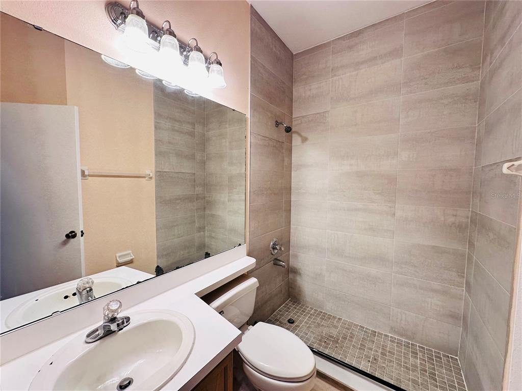 A bathroom features a vanity with a sink, a mirror, and a tiled walk-in shower — 13343 SUMMERTON DRIVE, ORLANDO, FL
