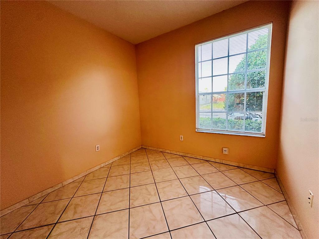 An empty room features peach-colored walls, a large window with blinds, and light-colored tile flooring — 13343 SUMMERTON DRIVE, ORLANDO, FL