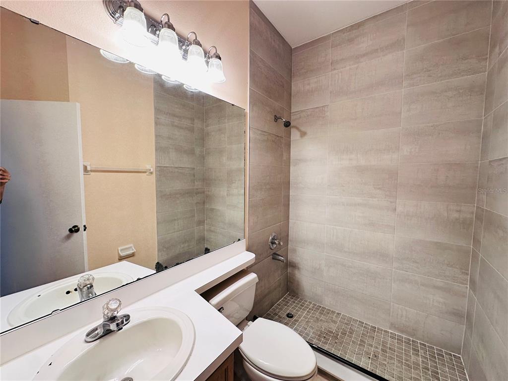 A bathroom features a vanity with a sink, a toilet, and a tiled walk-in shower — 13343 SUMMERTON DRIVE, ORLANDO, FL
