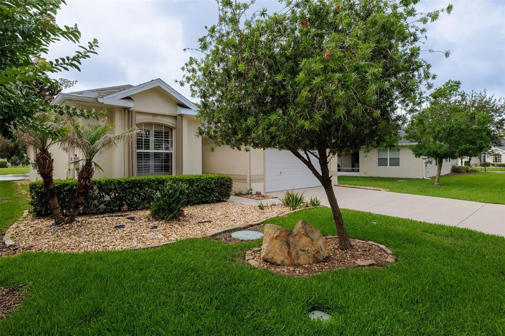 A single-story house with a beige exterior, a white garage door, and a landscaped front yard — 61 RAINTREE CIRCLE, PALM COAST, FL