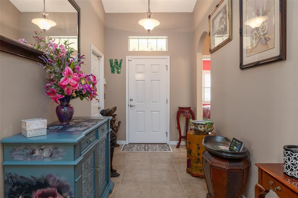 A foyer features a blue painted cabinet, tile flooring, a white door, and hanging lights — 61 RAINTREE CIRCLE, PALM COAST, FL