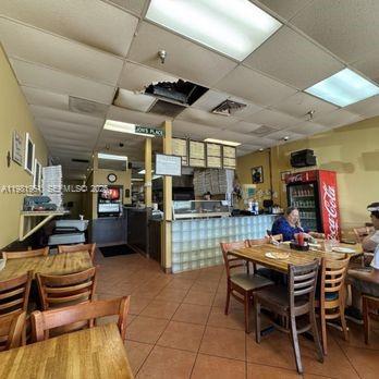 A restaurant interior features wooden tables, chairs, a service counter, and a drop ceiling — Powerline dr, Boca Raton FL 33433, BOCA RATON, FL