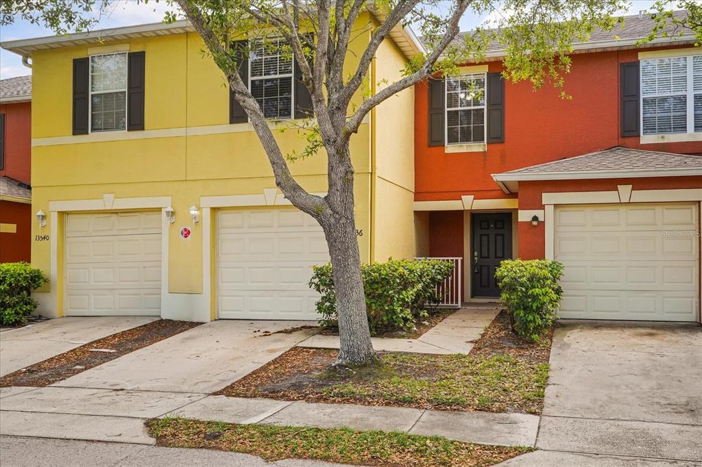 A view of the exterior of two attached townhomes with yellow and red stucco facades — 13536 TEA ROSE WAY UNIT 119, ORLANDO, FL