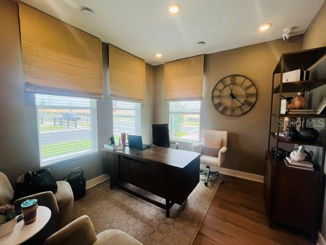 A home office features a dark wood desk, a beige chair, and a large wall clock — 15501 HAMLIN PARK DRIVE, WINTER GARDEN, FL