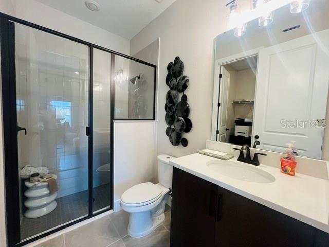 A bathroom features a glass-enclosed shower, a white toilet, and a vanity with a mirror — 15501 HAMLIN PARK DRIVE, WINTER GARDEN, FL