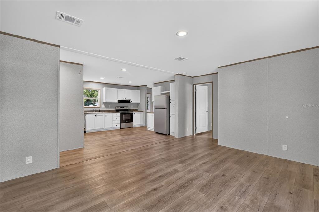 An open-concept living area features wood-look flooring and a kitchen with white cabinetry — 607 LAWRENCE STREET, WILDWOOD, FL