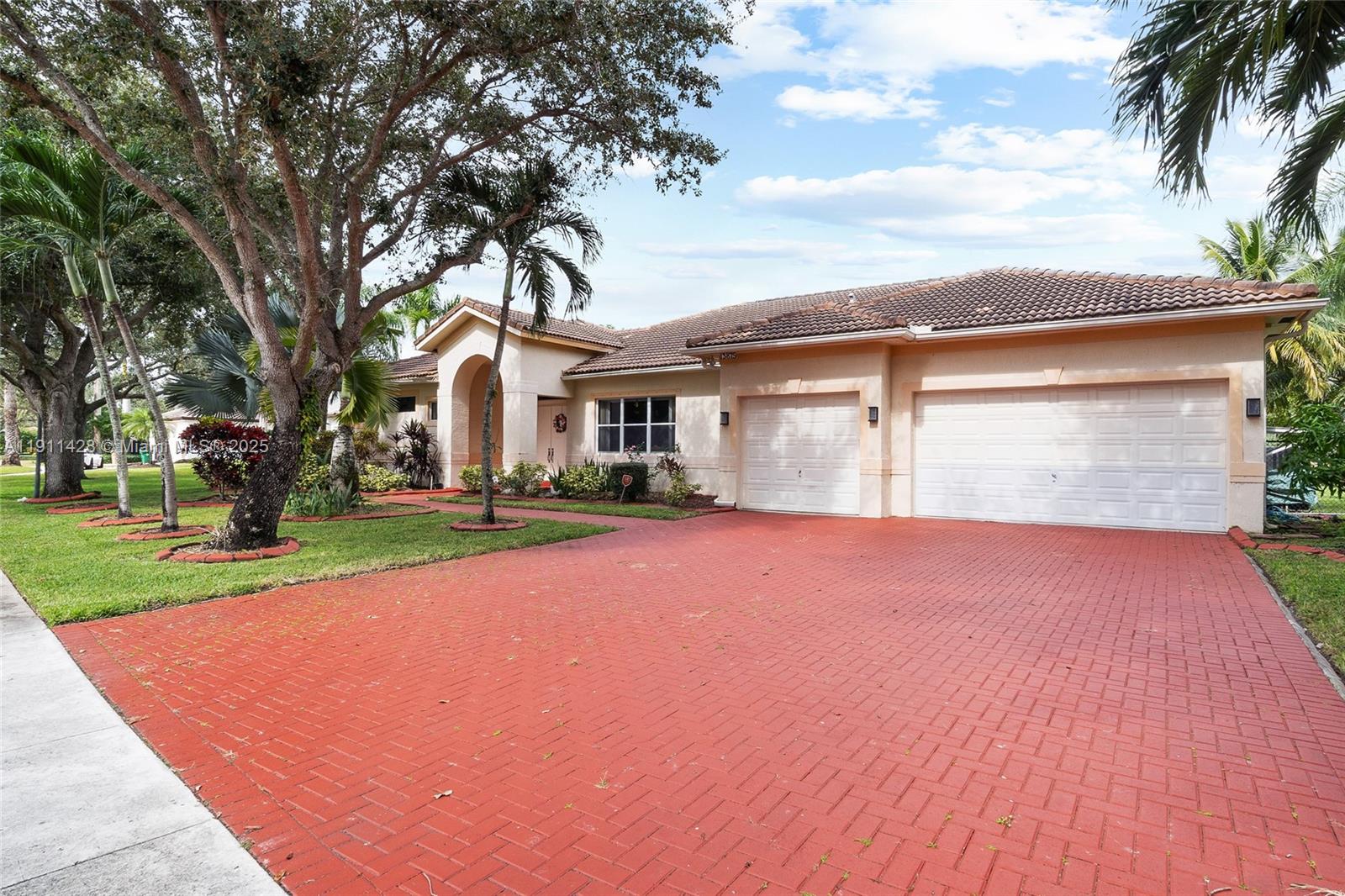 A single-story house with a red brick driveway, two-car garage, and mature trees — 13875 SW 41st St, Davie FL 33330, DAVIE, FL