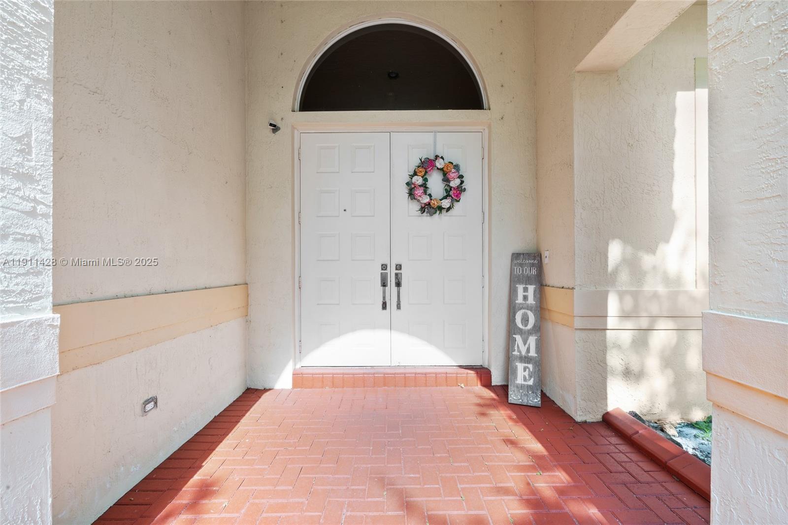 A front entryway features double white doors, a floral wreath, and a brick porch — 13875 SW 41st St, Davie FL 33330, DAVIE, FL