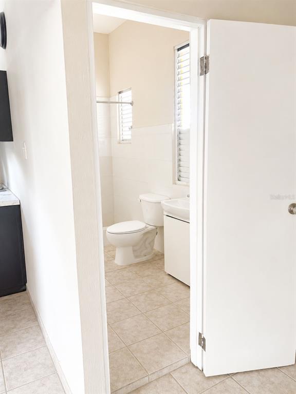 A bathroom with a toilet, vanity, and tiled floor is viewed through an open doorway — 54 CALLE DR. VEVE, BAYAMON, PR