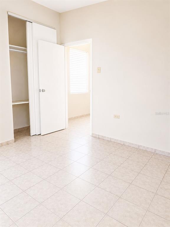 An empty room features light-colored tile flooring, a white closet, and a doorway to another room — 54 CALLE DR. VEVE, BAYAMON, PR