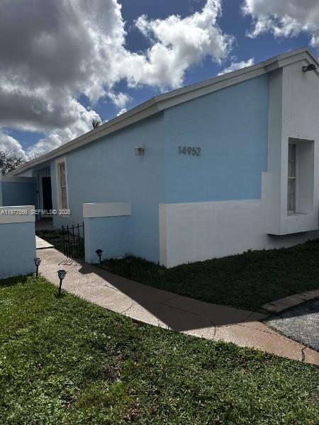 A light blue house exterior features a concrete walkway and a small patch of grass — 14952 SW 75th Ter, Miami FL 33193, MIAMI, FL