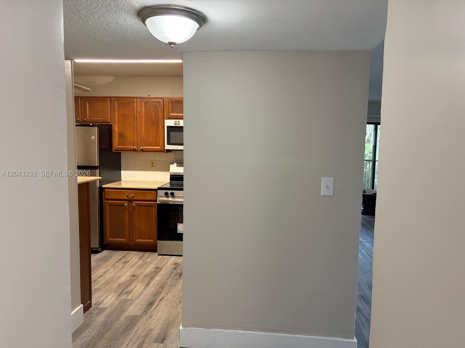 A kitchen with wood cabinets and stainless steel appliances is visible past a partition wall — 3400 Foxcroft Rd # 215, Miramar FL 33025, MIRAMAR, FL