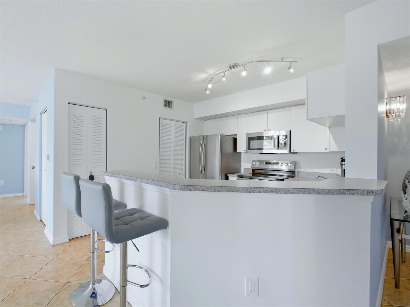 A kitchen with white cabinets, stainless steel appliances, and a breakfast bar with gray stools — 316 Villa Circle, Boynton Beach FL 33435, BOYNTON BEACH, FL