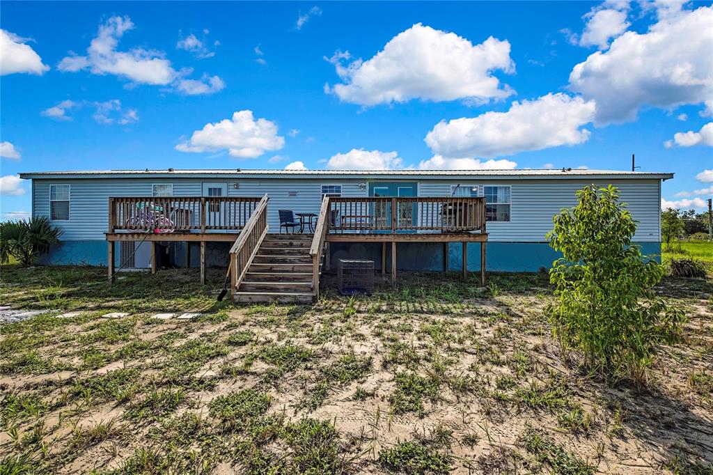 The exterior of a manufactured home features a wooden deck with stairs and a yard — 11089 FULMAR ROAD, WEEKI WACHEE, FL