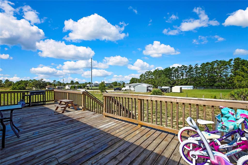 A wooden deck features a railing, a small picnic table, and several children's bicycles — 11089 FULMAR ROAD, WEEKI WACHEE, FL
