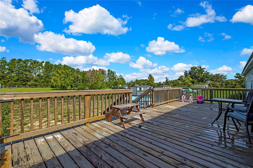 A wooden deck overlooks a grassy yard with a small picnic table and children's bicycles — 11089 FULMAR ROAD, WEEKI WACHEE, FL