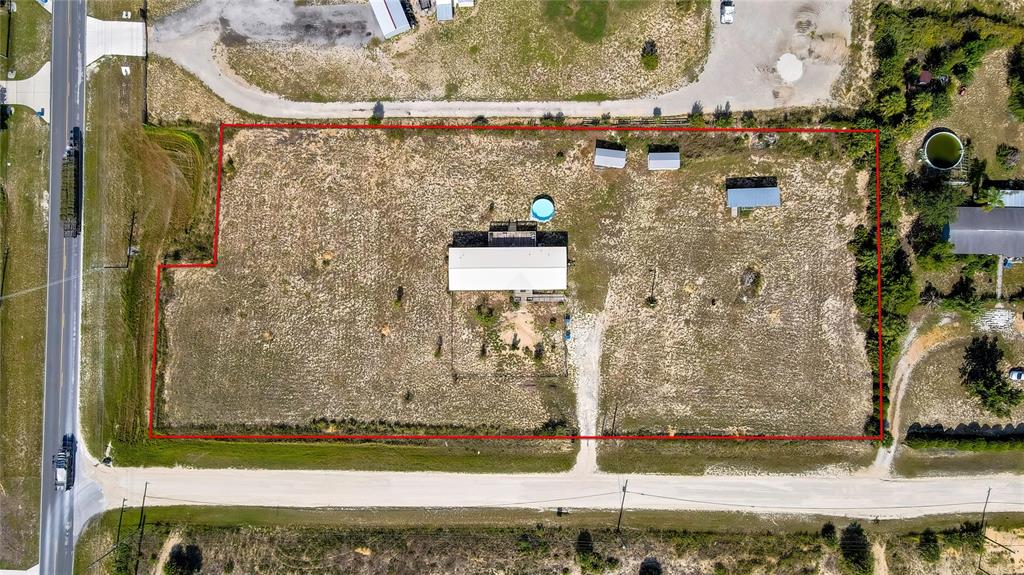 This aerial view shows a rectangular property with a house, outbuildings, and a pool — 11089 FULMAR ROAD, WEEKI WACHEE, FL