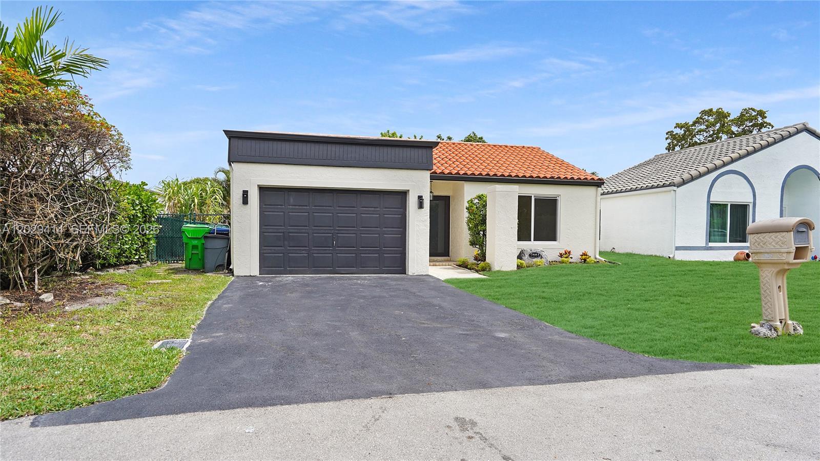 A single-story house features a dark garage door, a tiled roof, and a paved driveway — 9661 NW 44th Ct, Sunrise FL 33351, SUNRISE, FL
