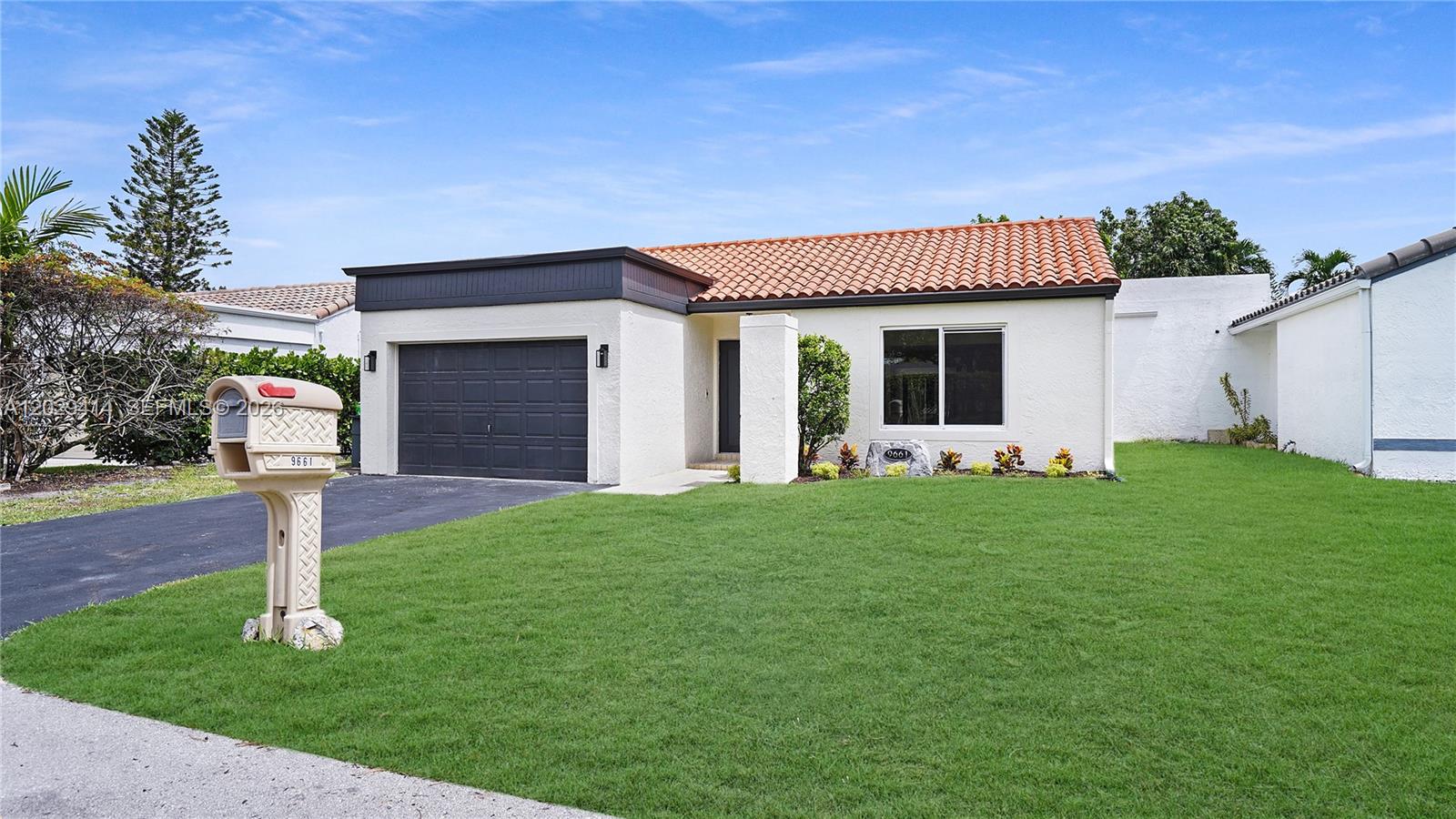 A single-story house with a terracotta tile roof, dark garage door, and a front lawn — 9661 NW 44th Ct, Sunrise FL 33351, SUNRISE, FL