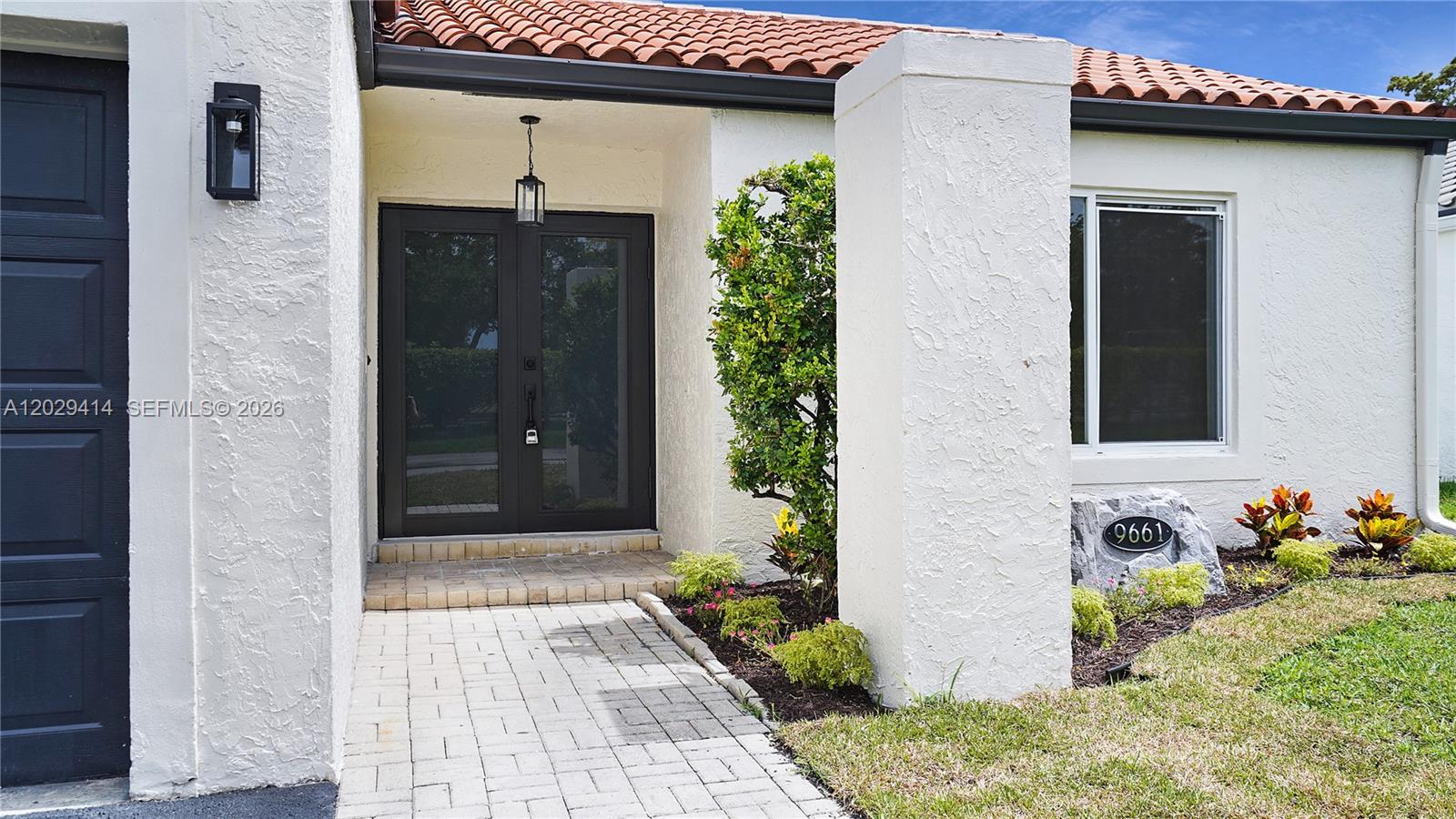 The exterior of a house features a brick walkway leading to dark double front doors — 9661 NW 44th Ct, Sunrise FL 33351, SUNRISE, FL