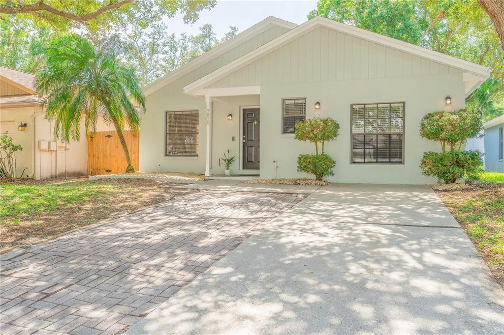 A light green single-story house features a paved driveway, a front porch, and mature trees — 3826 LAKE SHORE DRIVE, PALM HARBOR, FL
