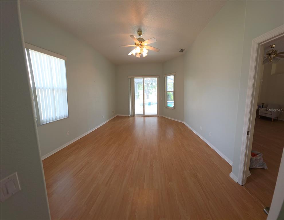 An empty room with light wood flooring, a ceiling fan, and sliding glass doors — 1028 ARCHWAY DRIVE, SPRING HILL, FL