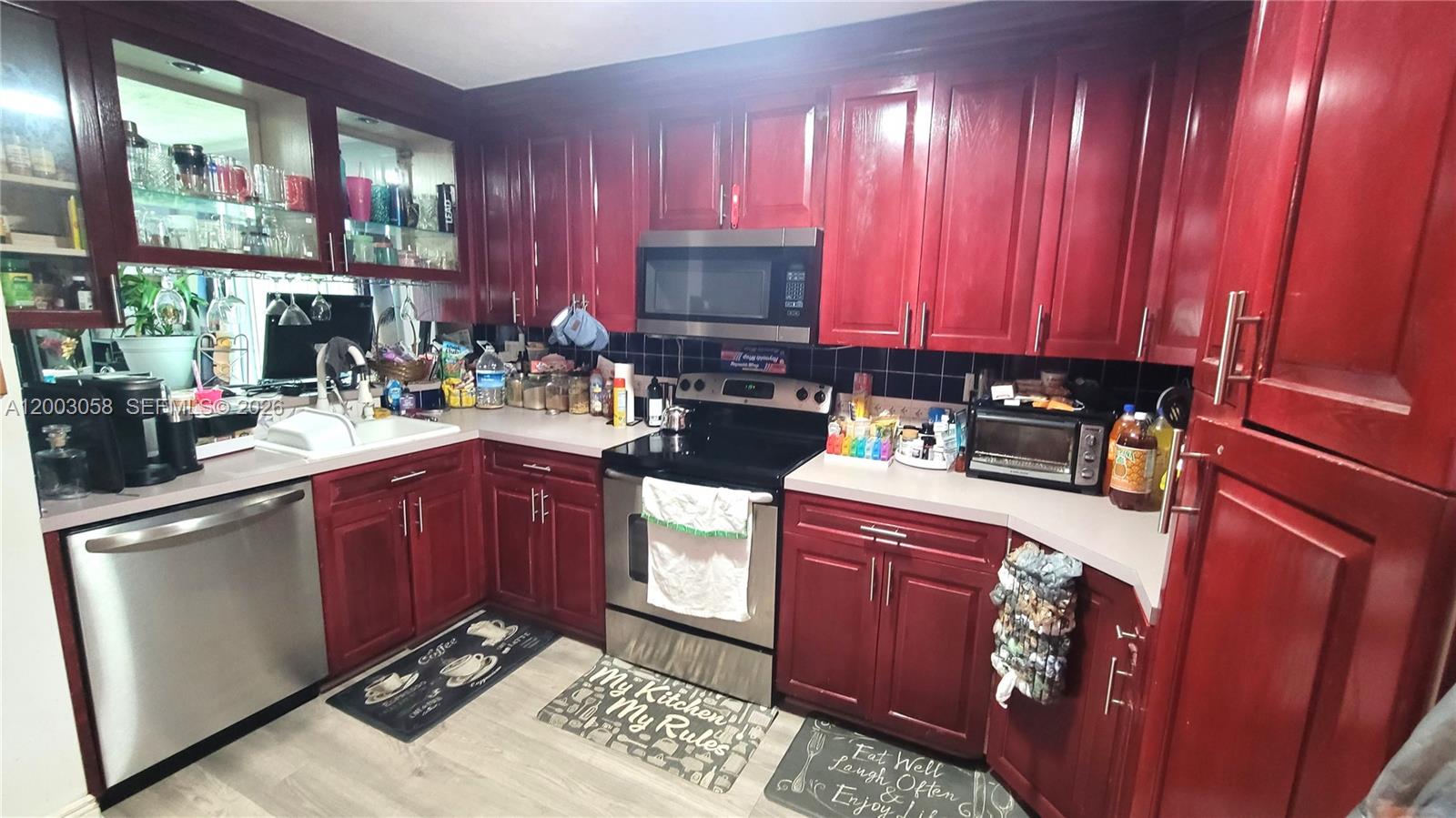 A kitchen features red wooden cabinets, stainless steel appliances, and a black tiled backsplash — 22113 SW 97th Ct, Cutler Bay FL 33190, CUTLER BAY, FL