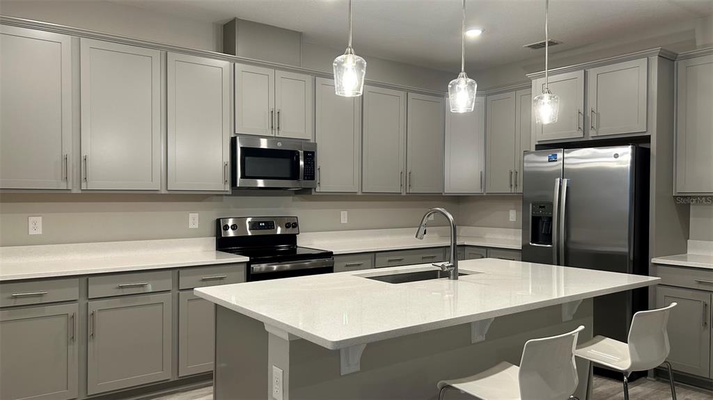 A kitchen features gray cabinets, white countertops, stainless steel appliances, and a central island — 367 SOFIA LANE, LAKE ALFRED, FL