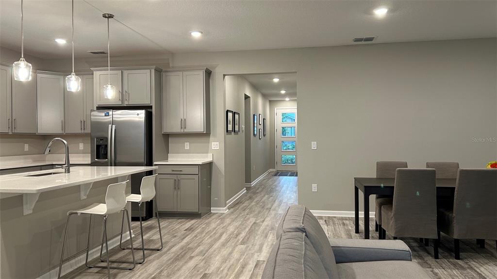 An open-concept kitchen with gray cabinets, a white island, and a dining area — 367 SOFIA LANE, LAKE ALFRED, FL
