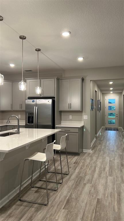 A kitchen features gray cabinets, stainless steel appliances, a white island, and light wood flooring — 367 SOFIA LANE, LAKE ALFRED, FL