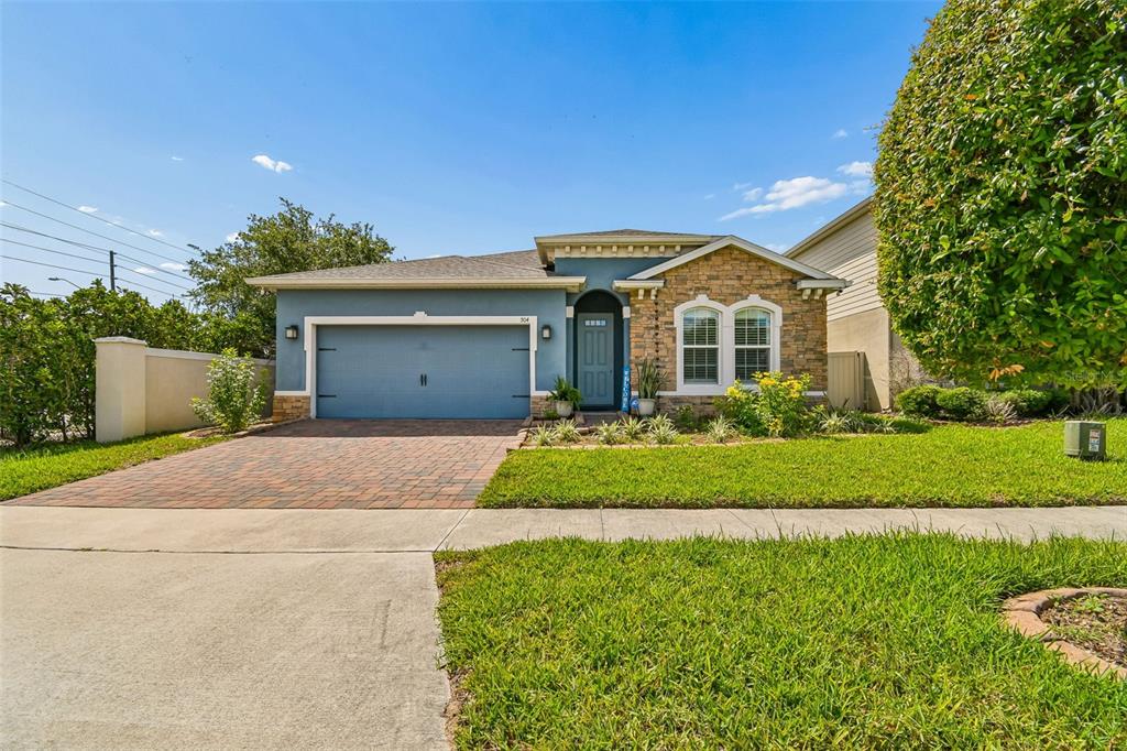 A single-story house with a blue garage, stone facade, and a paved driveway — 504 AFFIRMED WAY, DAVENPORT, FL