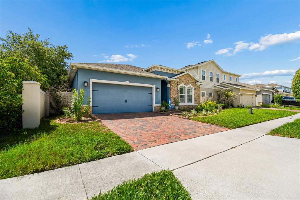 A blue single-story house with a stone facade and a brick paver driveway — 504 AFFIRMED WAY, DAVENPORT, FL