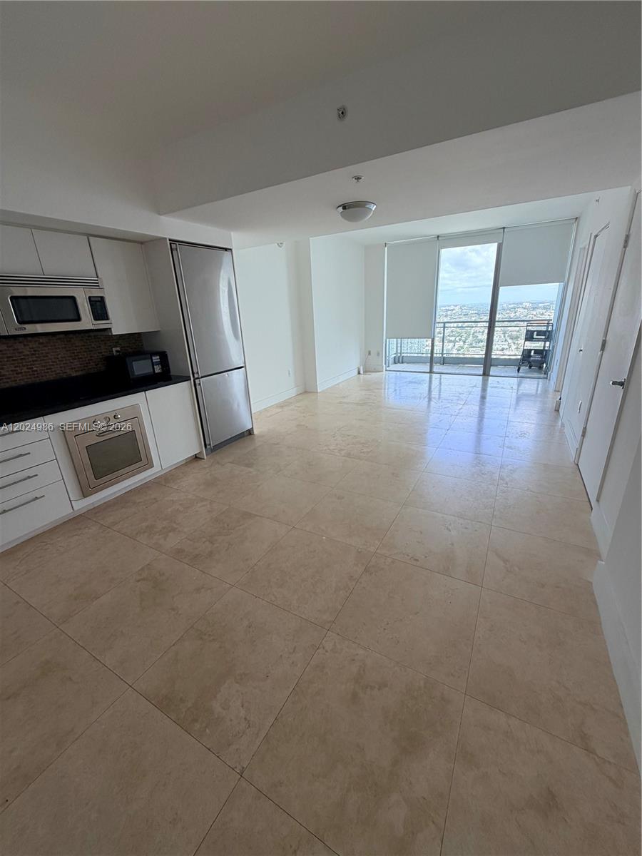 A kitchen with white cabinets and stainless steel appliances opens to a living area — 92 SW 3rd St # 3909, Miami FL 33130, MIAMI, FL