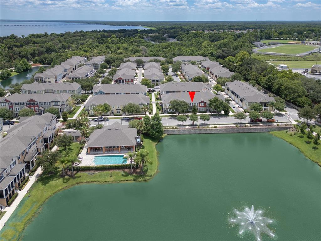 An aerial view shows a multi-story apartment complex situated next to a large pond — 453 GEE HAMMOCK LANE, WINTER SPRINGS, FL